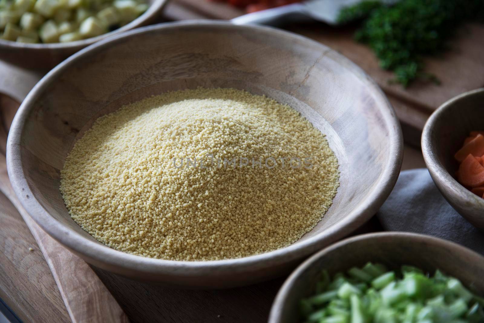 Polenta in wooden bowl on table with other ingredients.