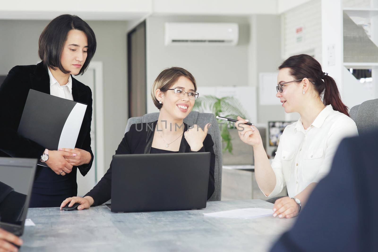 Three young successful business women in the office, together, happily working on a project. 