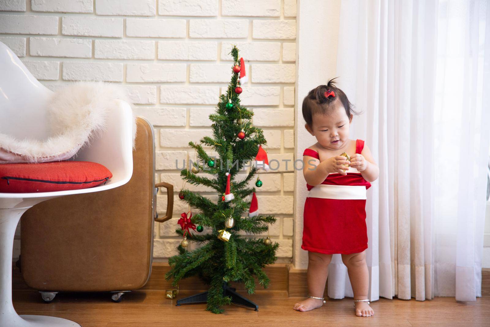 Full Length Of Cute Baby Girl Wearing Santa Costume While Sitting With Christmas Decorations by chuanchai