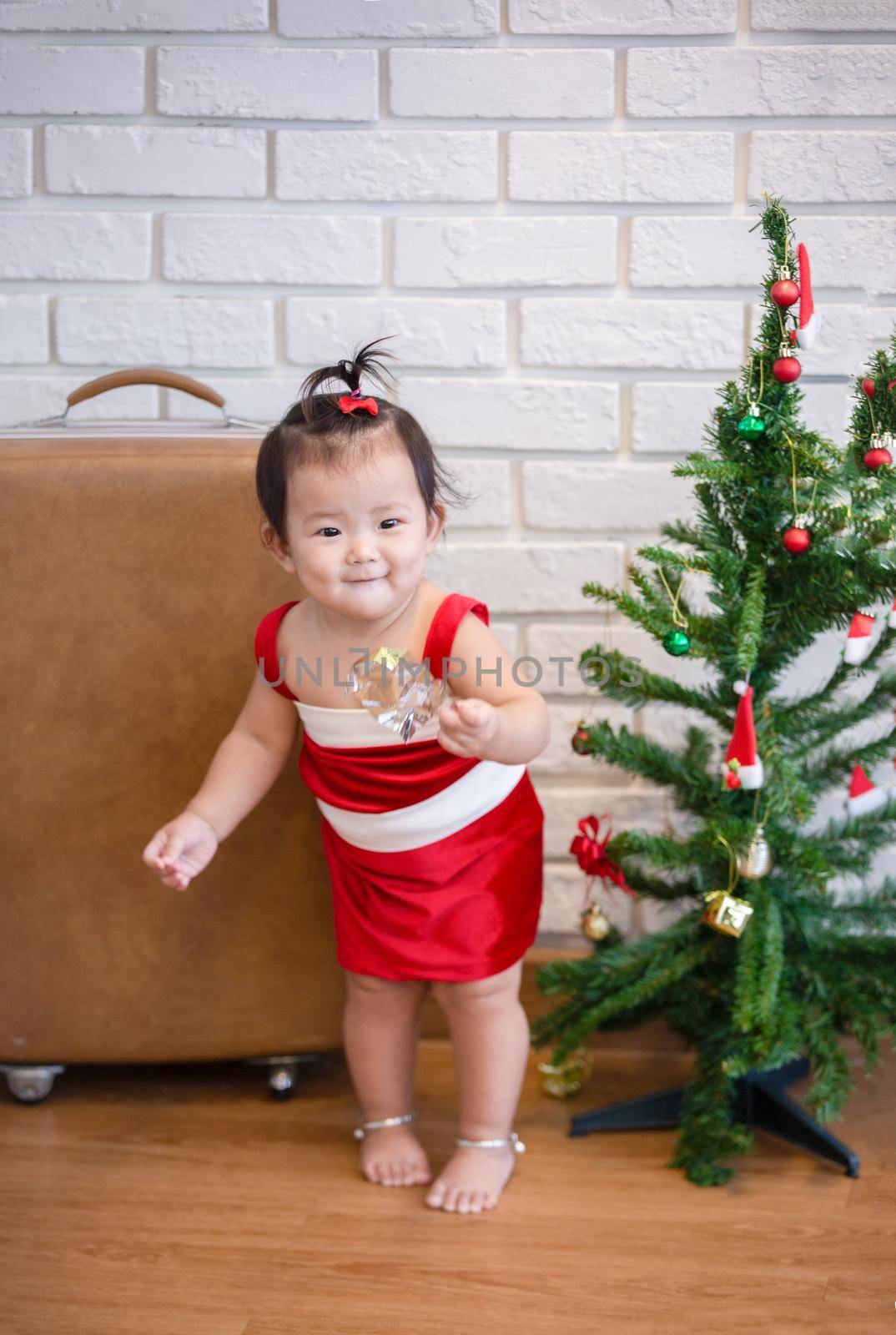 Full Length Of Cute Baby Girl Wearing Santa Costume While Sitting With Christmas Decorations