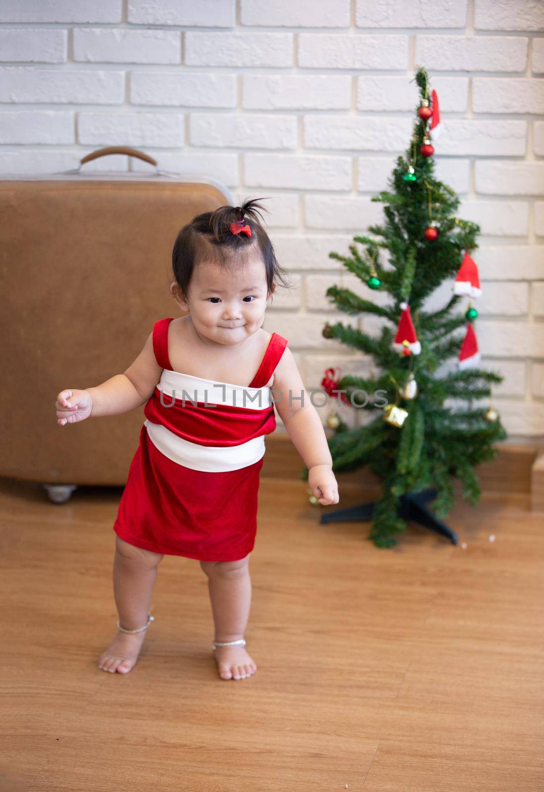 Full Length Of Cute Baby Girl Wearing Santa Costume While Sitting With Christmas Decorations