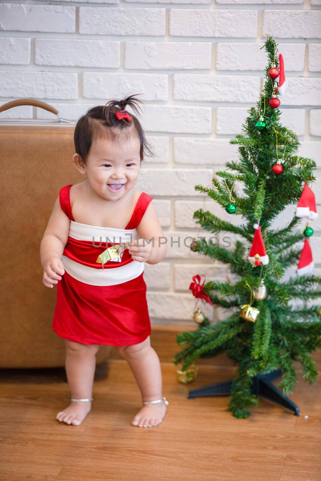 Full Length Of Cute Baby Girl Wearing Santa Costume While Sitting With Christmas Decorations