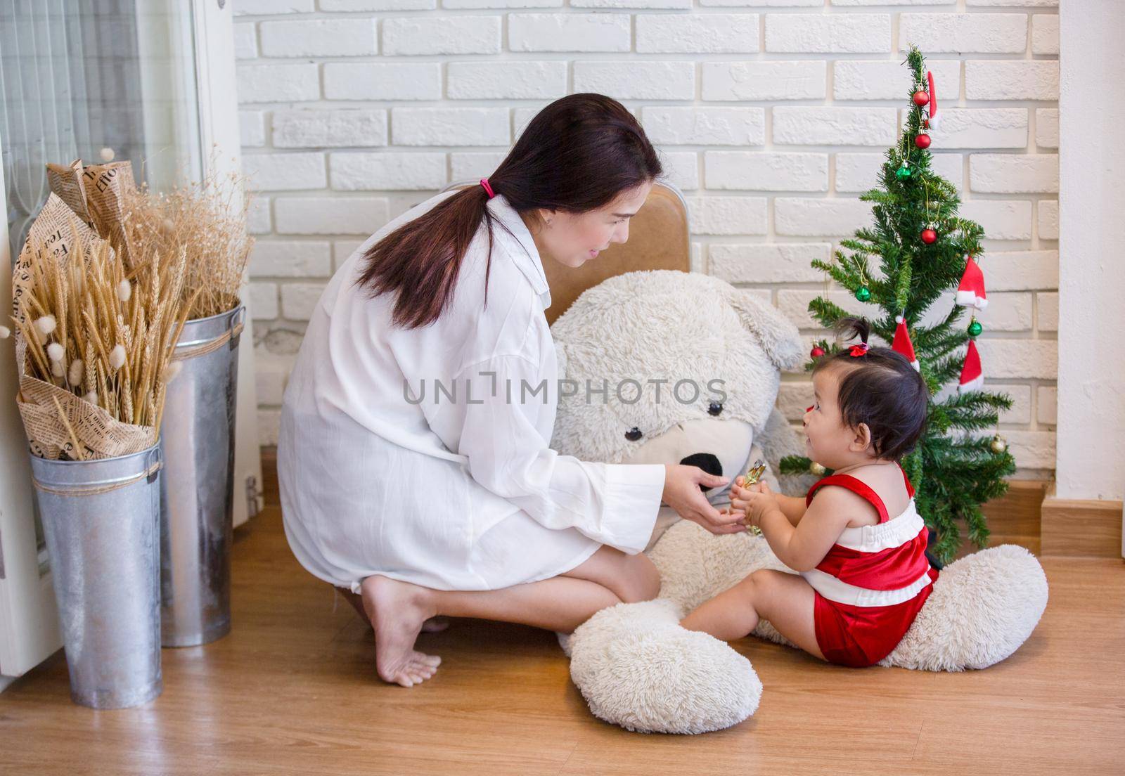 Full Length Of Cute Baby Girl Wearing Santa Costume While Sitting With Christmas Decorations by chuanchai