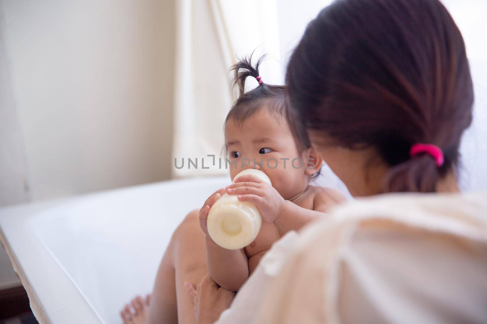 Side view of loving mother with newborn baby indoors at home. by chuanchai