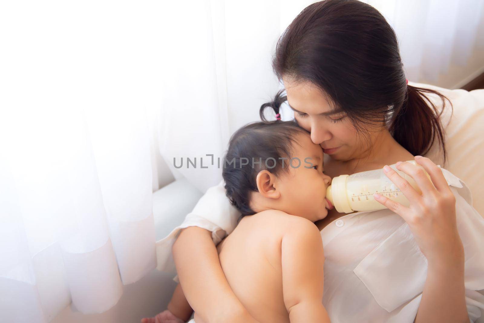Loving and affectionate mother holding newborn baby indoors at home.