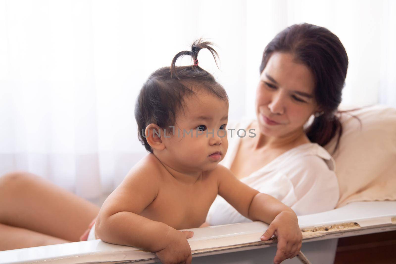 Side view of loving mother with newborn baby indoors at home. by chuanchai