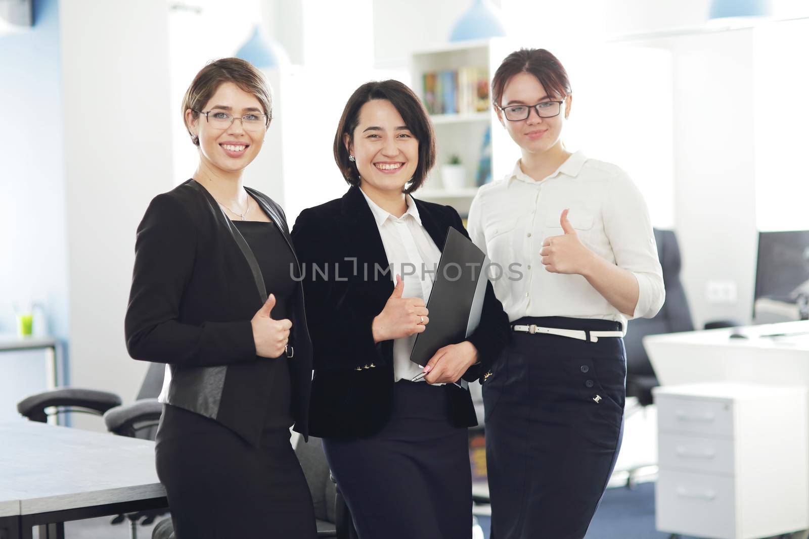 Three young successful business women in the office smiling happily by selinsmo