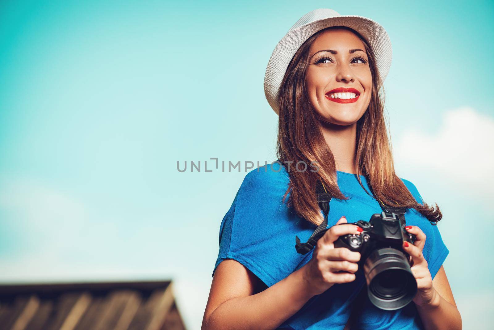 Young beautiful woman standing by viewpoint and holding digital camera.