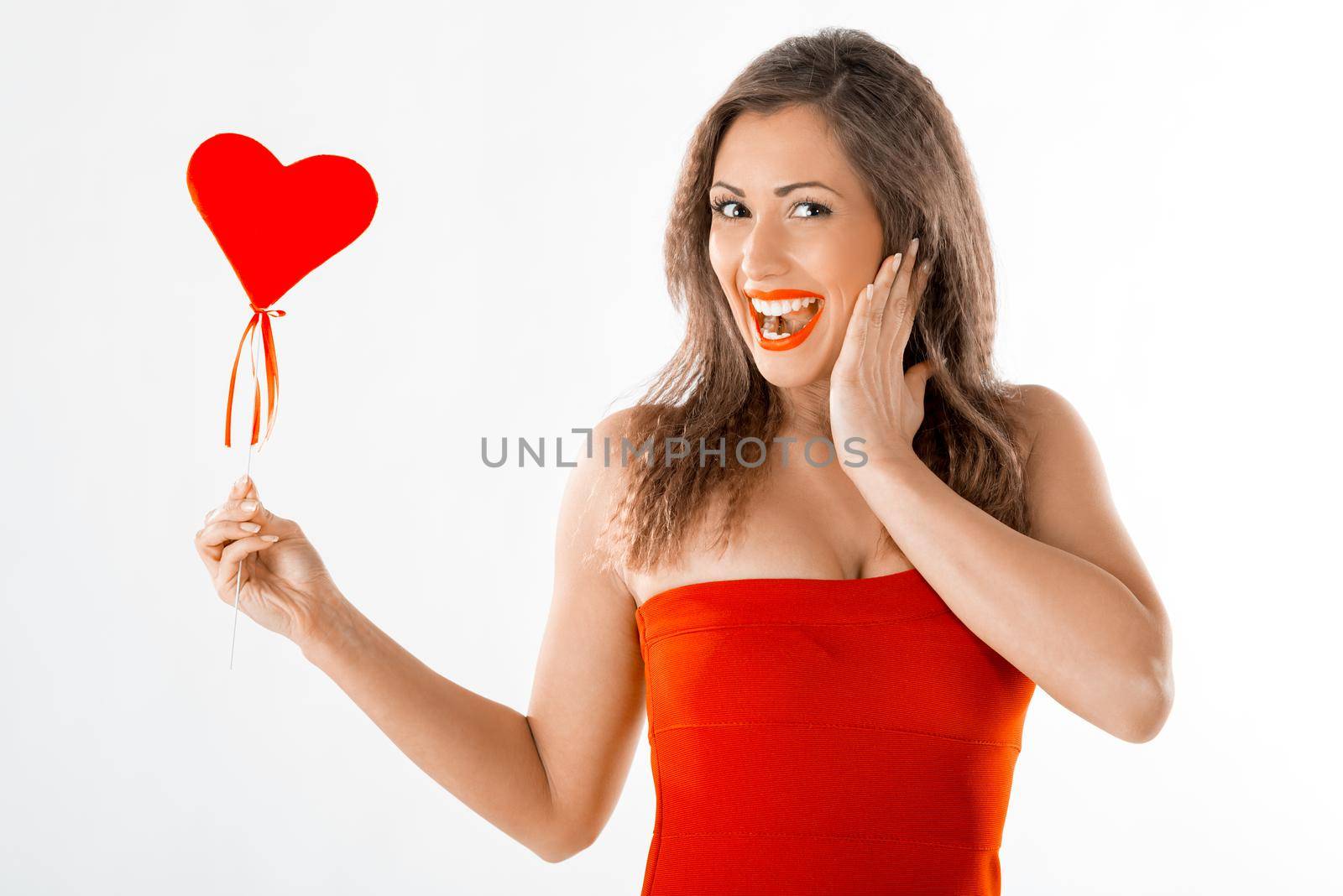 Beautiful cheerful girl standing and holding red heart.