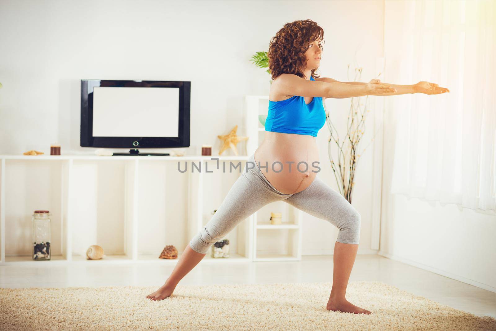 Beautiful young pregnant woman doing yoga exercise at the home.