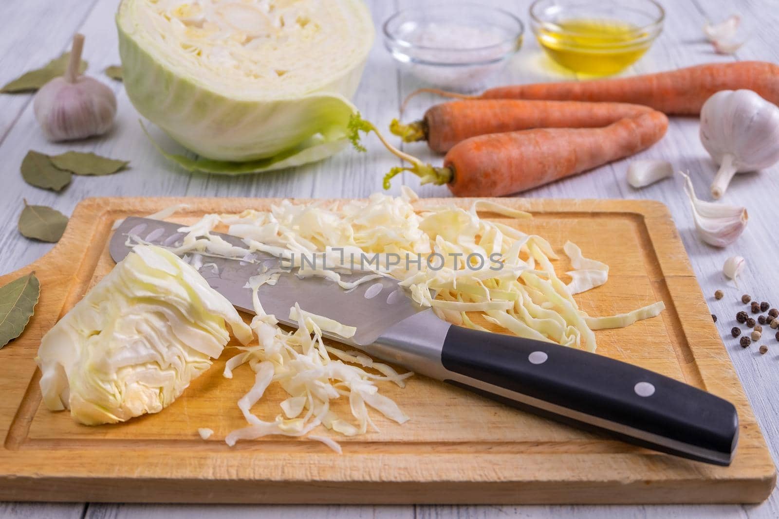 Close-up of a kitchen workspace with the process of shredding white cabbage and the ingredients for its fermentation or cooking