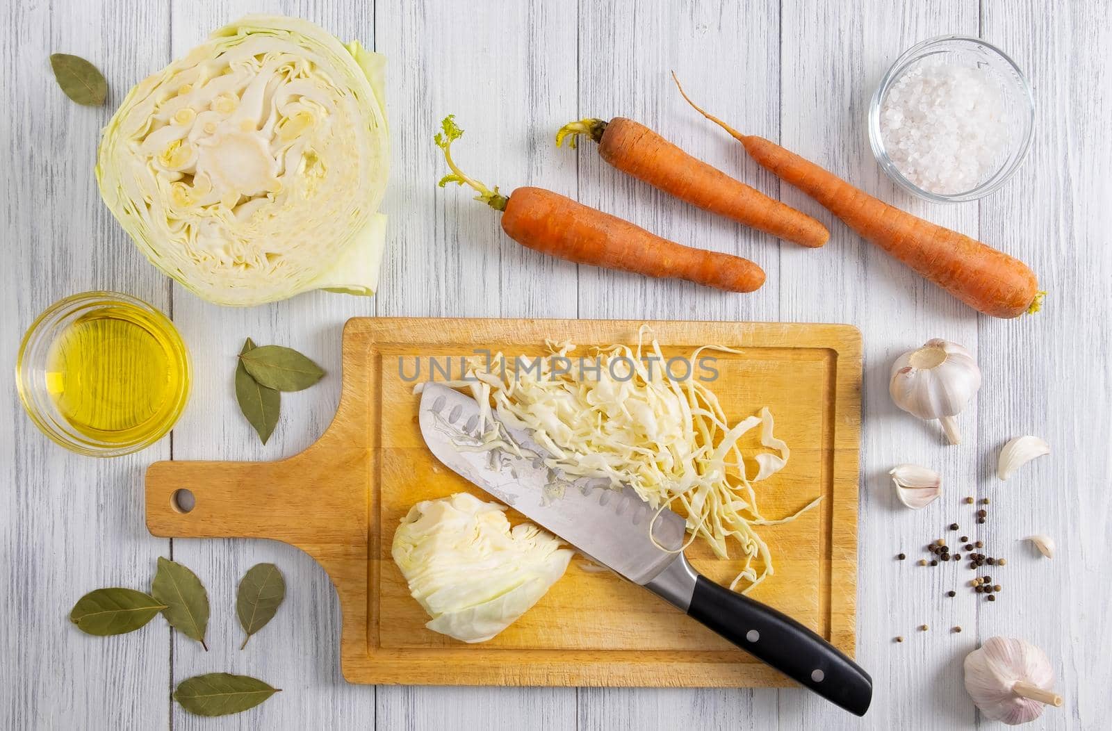 Top view of kitchen workspace with white cabbage shredding process and ingredients for fermentation or cooking