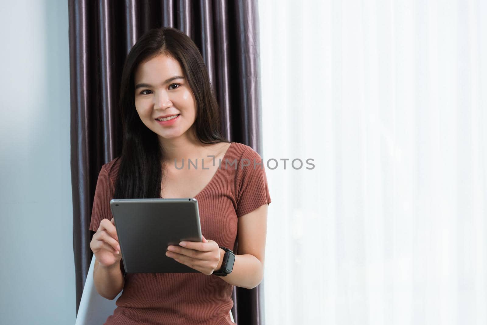 Work from home, Happy Asian young businesswoman smile video conference call or facetime by modern digital smart tablet computer she uses finger touching on screen, looking to camera at the home office