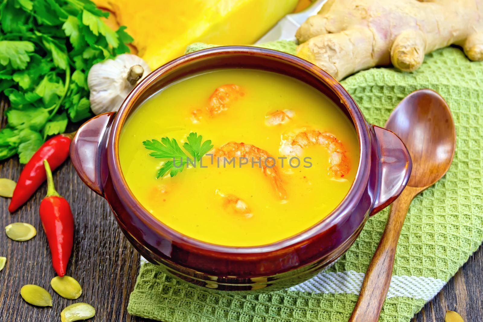Soup-puree pumpkin with shrimps in clay bowl on napkin by rezkrr