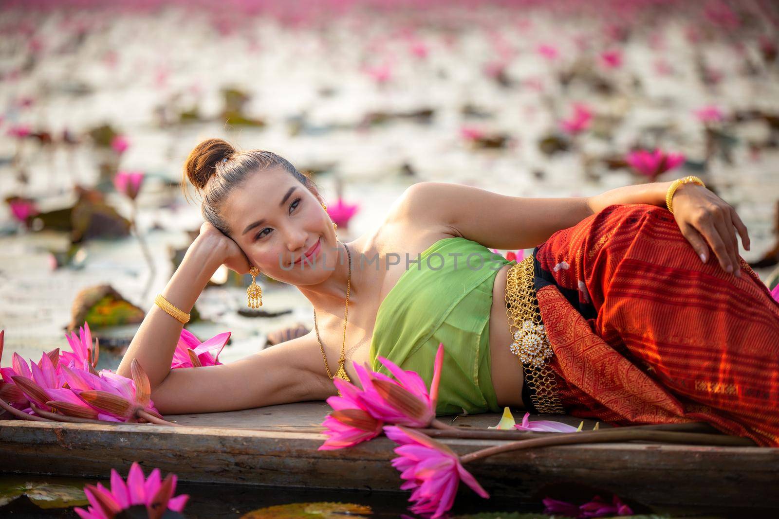 Young Asian women in Traditional dress in the boat and pink lotus flowers in the pond.Beautiful girls in traditional costume.Thai. Ayutthaya, elegance. by chuanchai