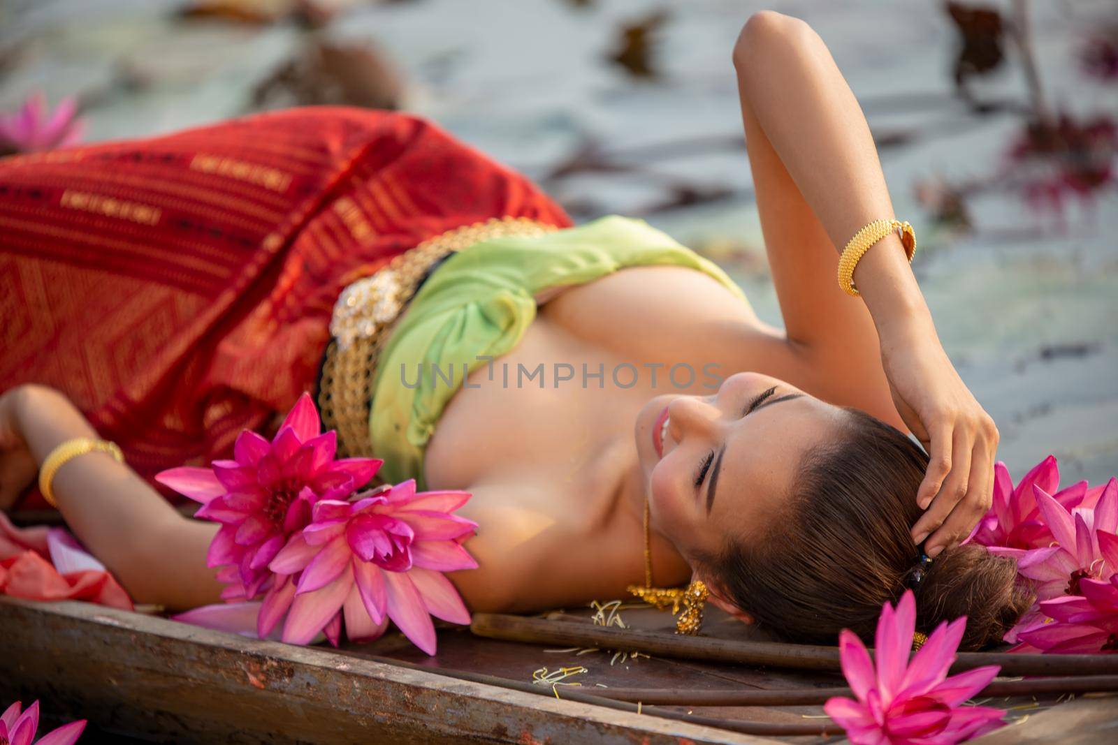 Young Asian women in Traditional dress in the boat and pink lotus flowers in the pond.Beautiful girls in traditional costume.Thai. Ayutthaya, elegance.