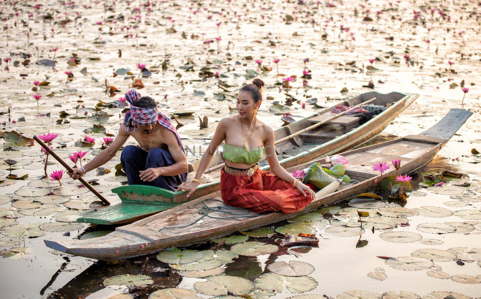 Young Asian women in Traditional dress in the boat and pink lotus flowers in the pond.Beautiful girls in traditional costume.Thai. Ayutthaya, elegance. by chuanchai