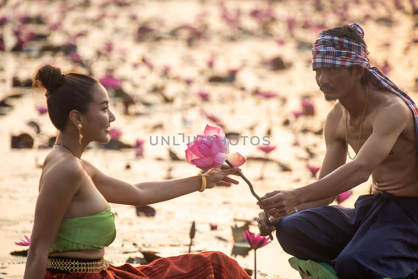 Young Asian women in Traditional dress in the boat and pink lotus flowers in the pond.Beautiful girls in traditional costume.Thai. Ayutthaya, elegance.