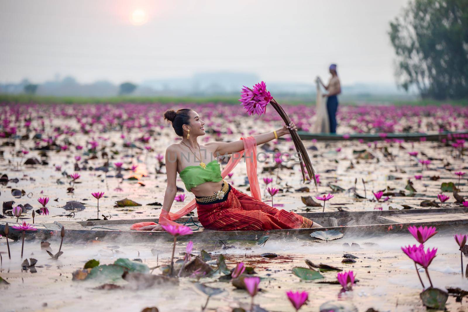 Young Asian women in Traditional dress in the boat and pink lotus flowers in the pond.Beautiful girls in traditional costume.Thai. Ayutthaya, elegance. by chuanchai