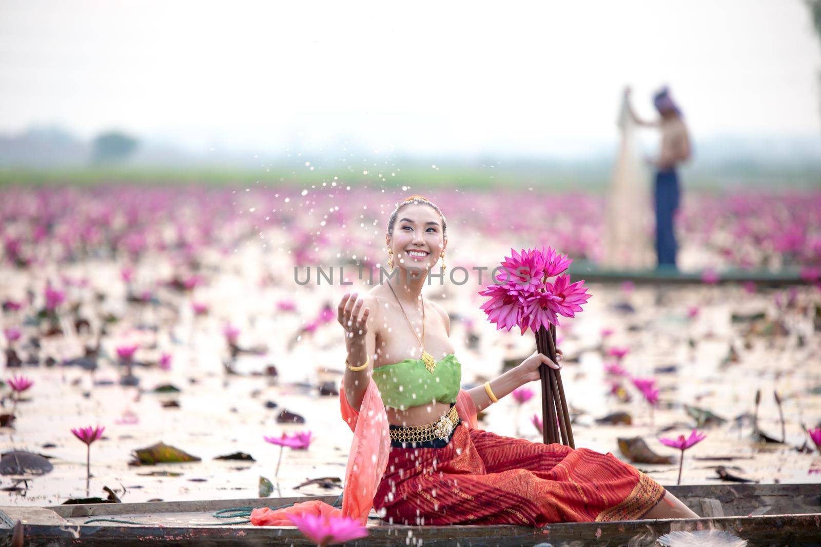 Young Asian women in Traditional dress in the boat and pink lotus flowers in the pond.Beautiful girls in traditional costume.Thai. Ayutthaya, elegance.