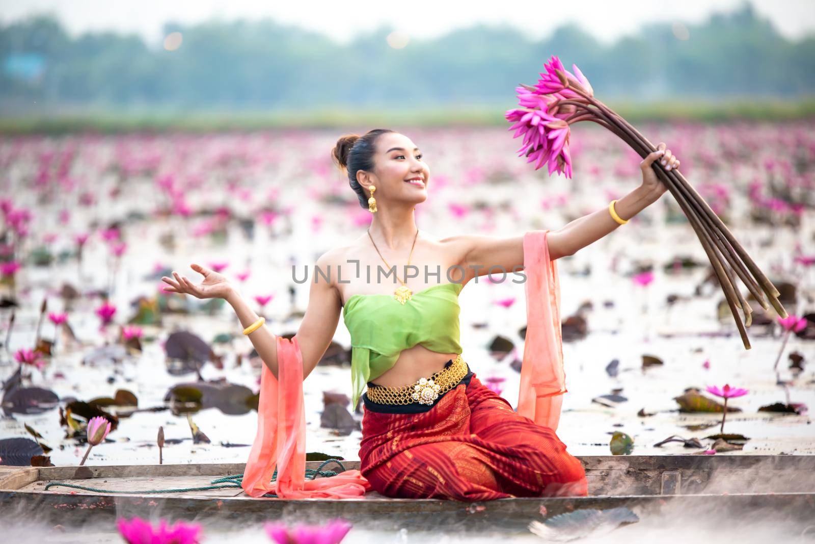 Young Asian women in Traditional dress in the boat and pink lotus flowers in the pond.Beautiful girls in traditional costume.Thai. Ayutthaya, elegance. by chuanchai