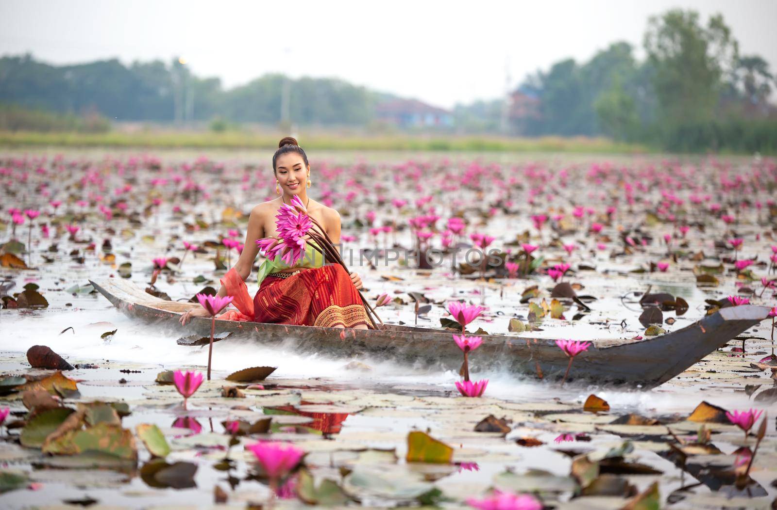 Young Asian women in Traditional dress in the boat and pink lotus flowers in the pond.Beautiful girls in traditional costume.Thai. Ayutthaya, elegance. by chuanchai