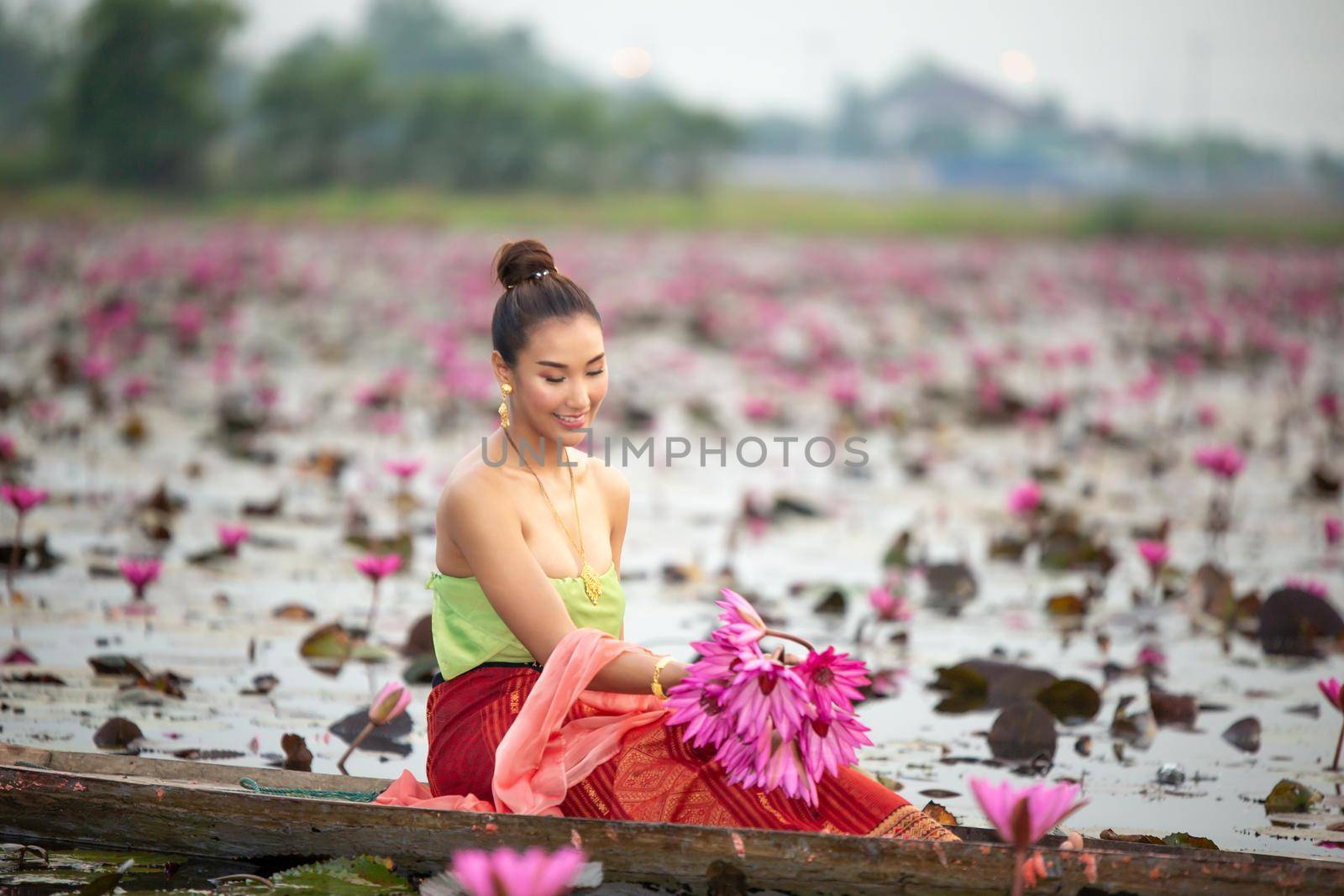 Young Asian women in Traditional dress in the boat and pink lotus flowers in the pond.Beautiful girls in traditional costume.Thai. Ayutthaya, elegance. by chuanchai