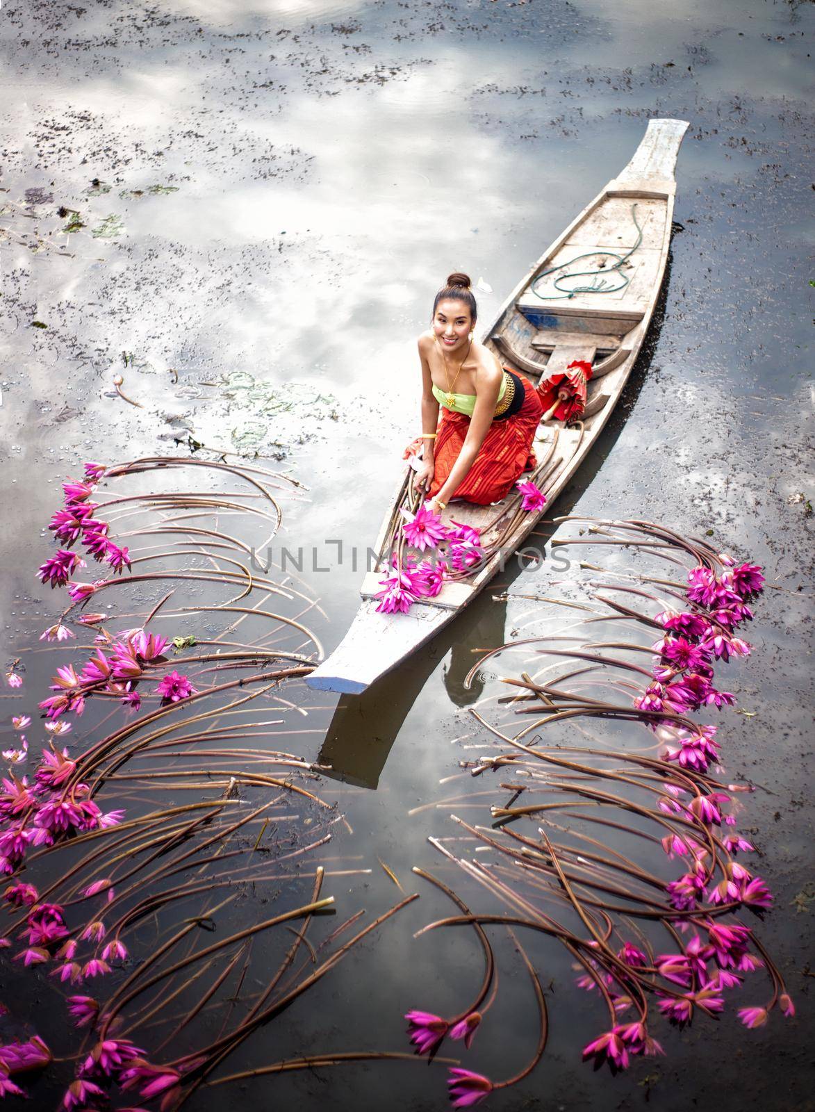 Young Asian women in Traditional dress in the boat and pink lotus flowers in the pond.Beautiful girls in traditional costume.Thai. Ayutthaya, elegance. by chuanchai