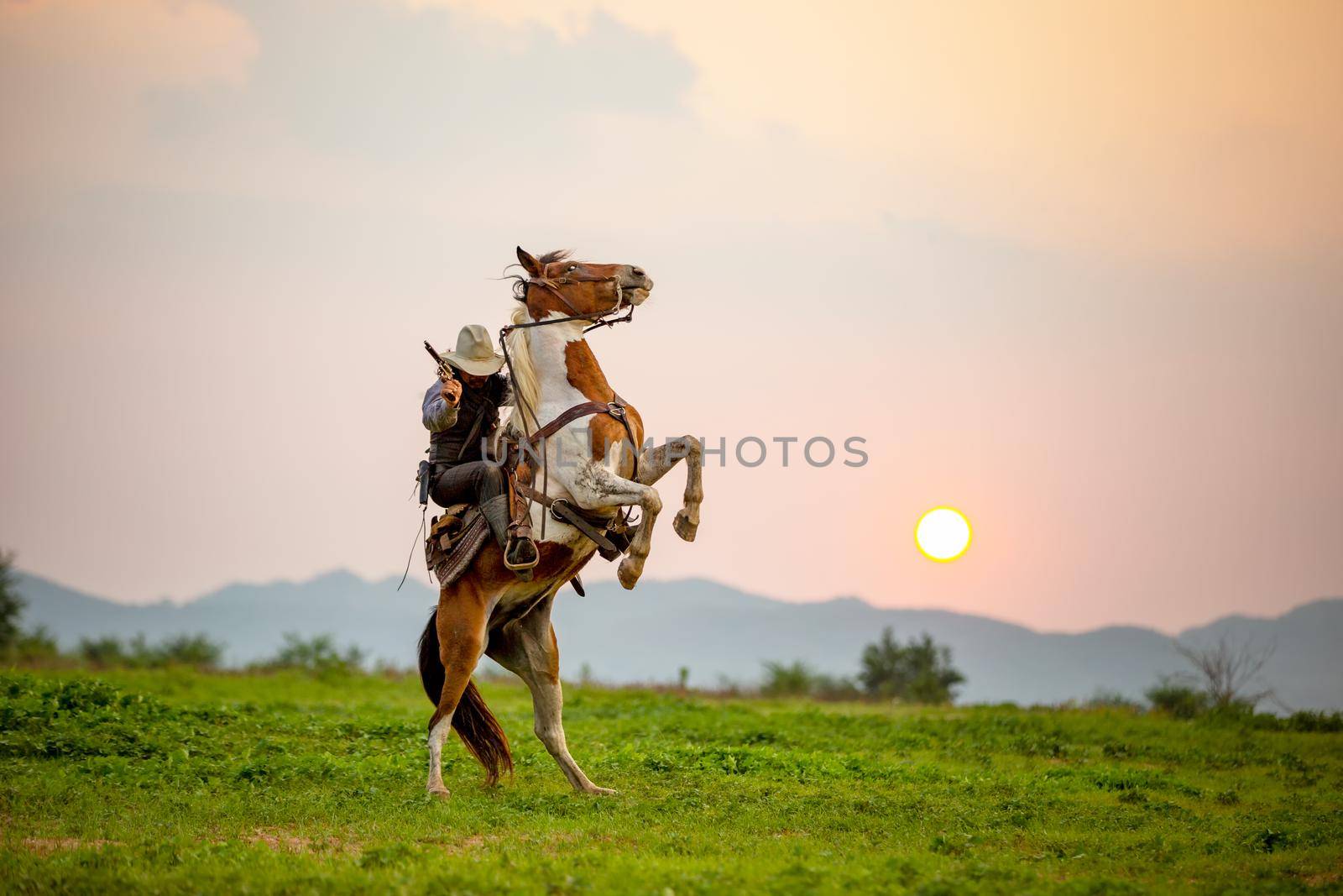 cowboy riding horse against sunset	 by chuanchai