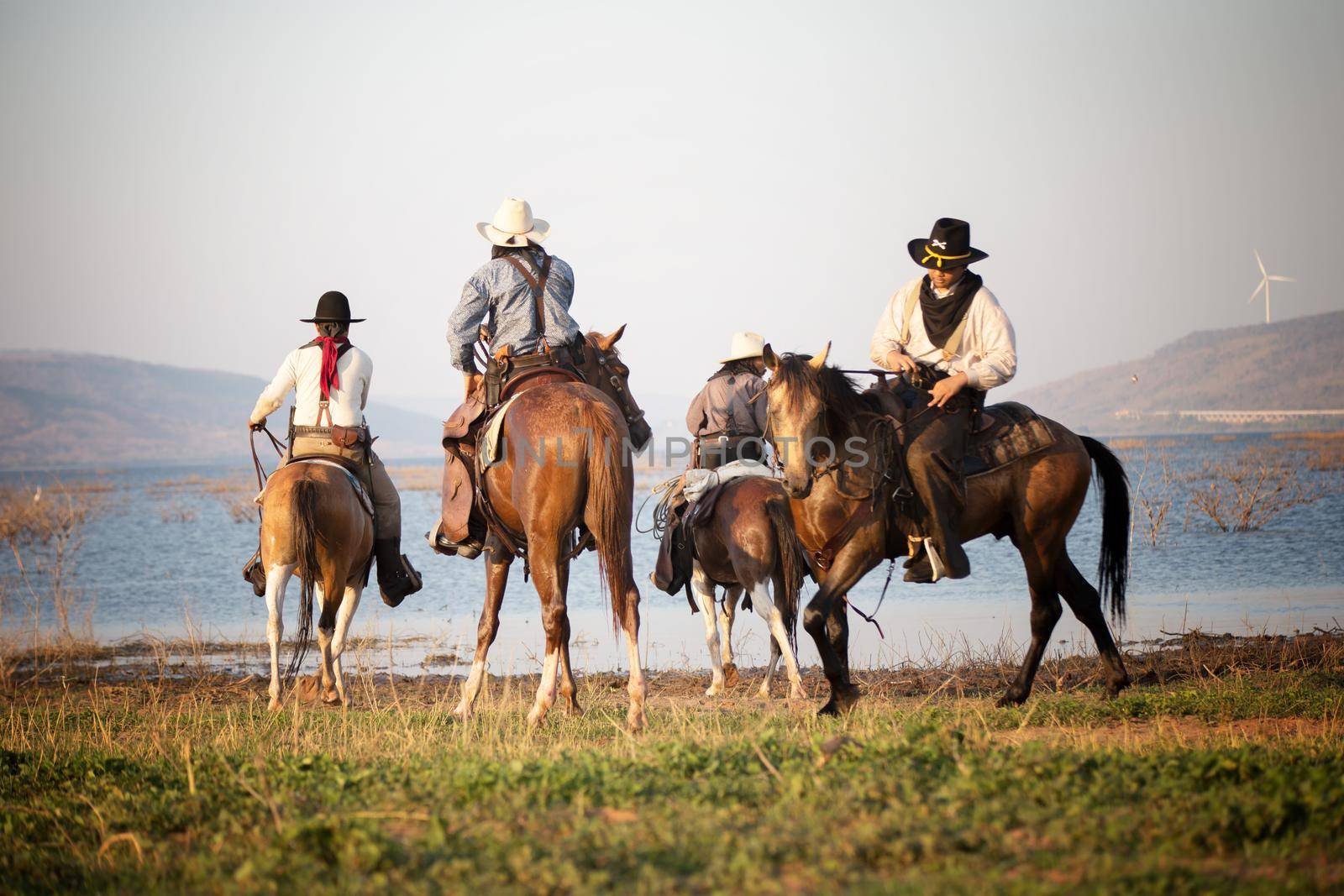 cowboy riding horse against sunset	 by chuanchai