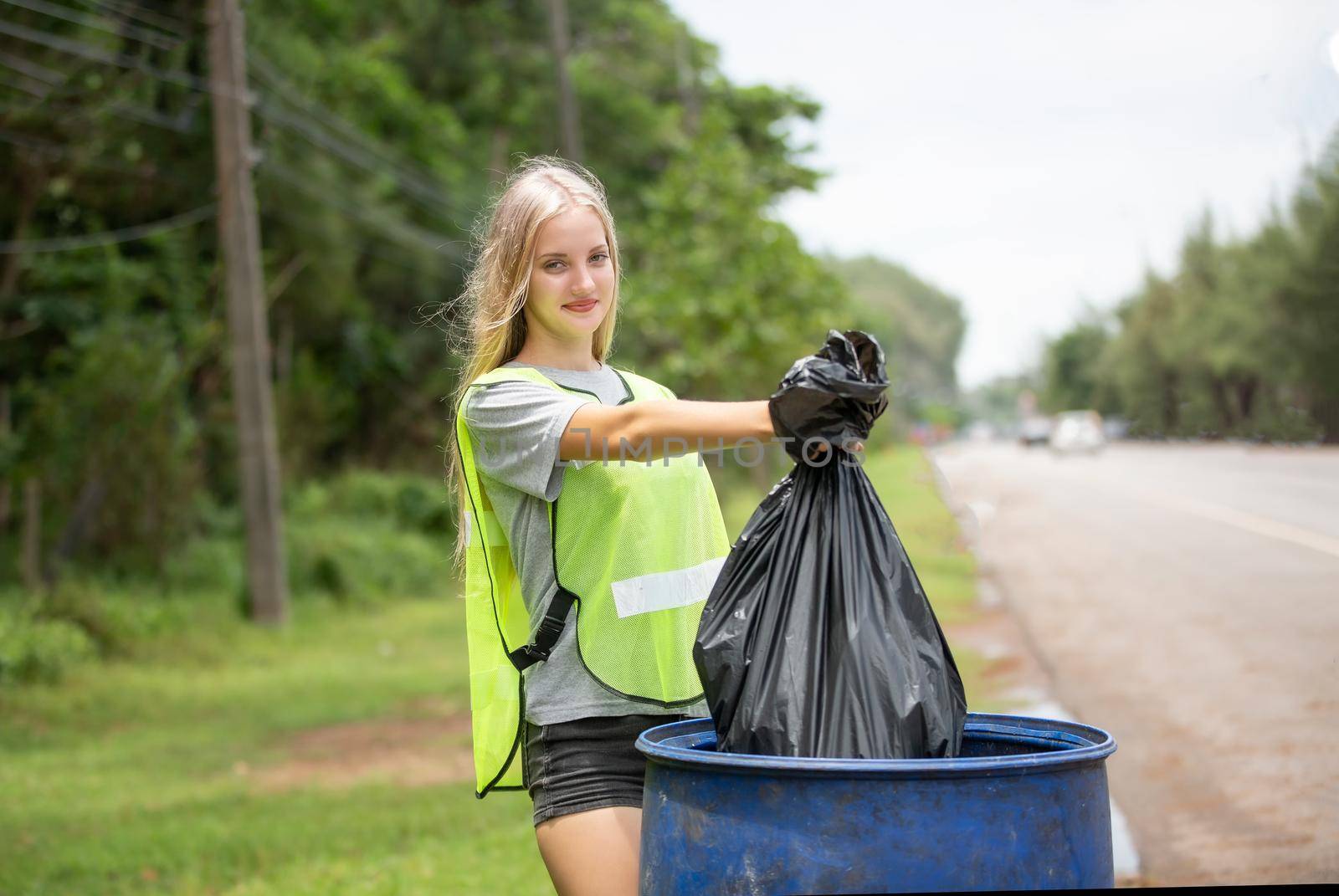 Green volunteering. Optimistic two volunteers holding garbage bag and help picking up trash at park, they're picking up the garbage and putting it in a black garbage bag. ecology protection concept. by chuanchai