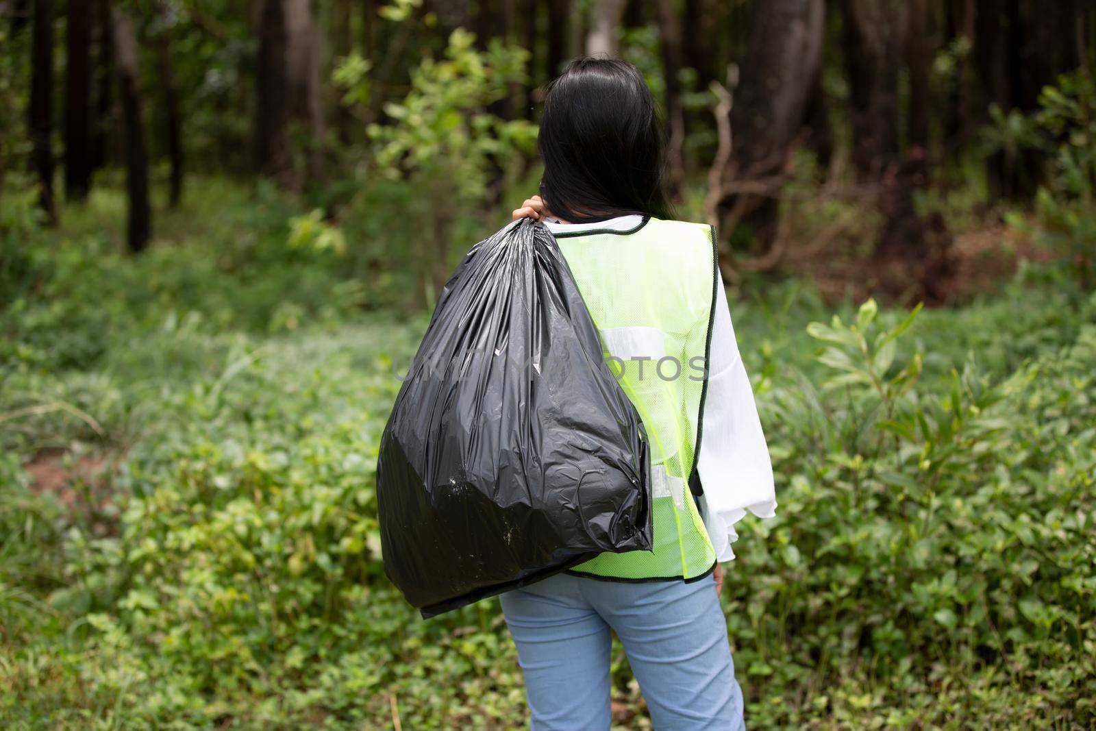 Green volunteering. Optimistic two volunteers holding garbage bag and help picking up trash at park, they're picking up the garbage and putting it in a black garbage bag. ecology protection concept.