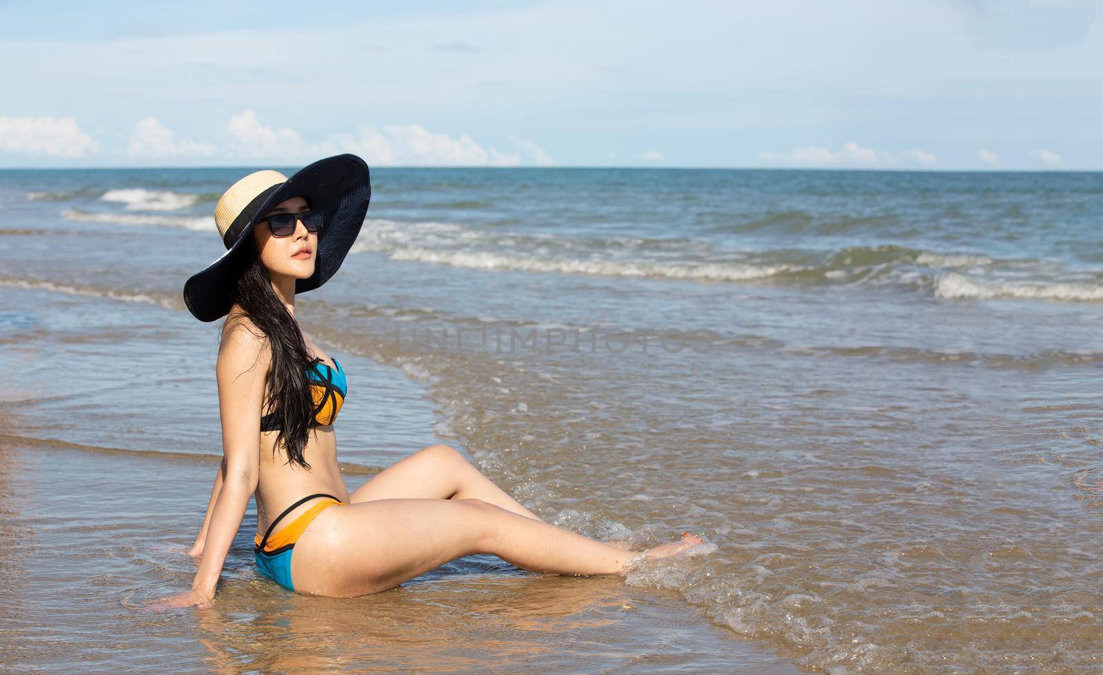 Beautiful young woman in sexy bikini on sand at sea beach.