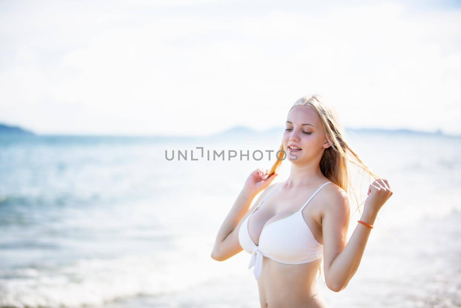 Beautiful young woman in sexy bikini on sand at sea beach.