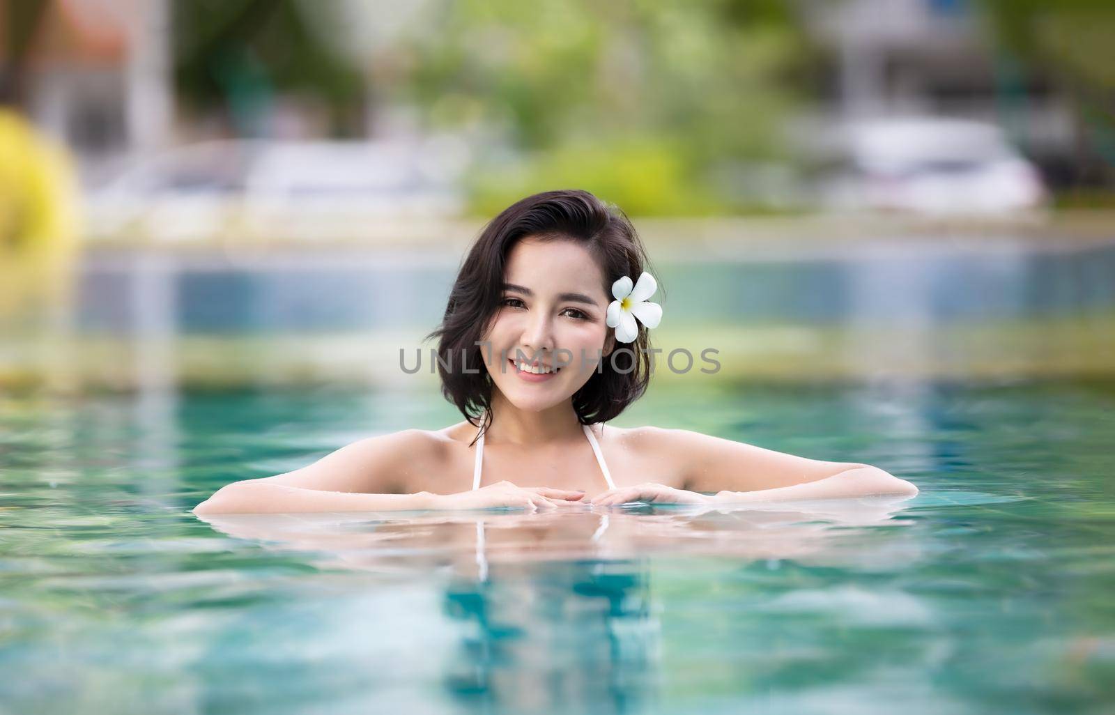 woman in white bikini tanning by the pool by chuanchai