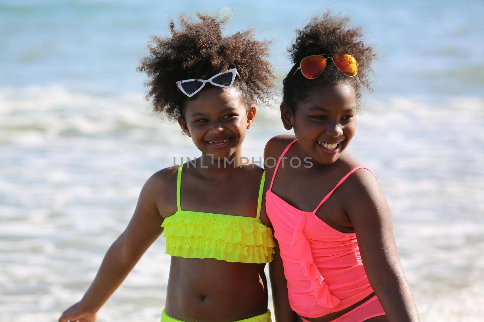 Kids playing running on sand at the beach, A group of children holding hands in a row on the beach in summer, rear view against sea and blue sky