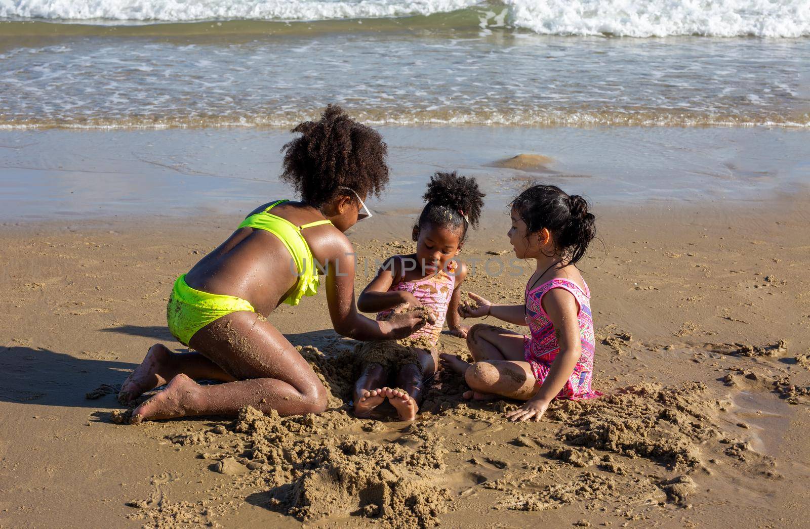 Kids playing running on sand at the beach, A group of children holding hands in a row on the beach in summer, rear view against sea and blue sky