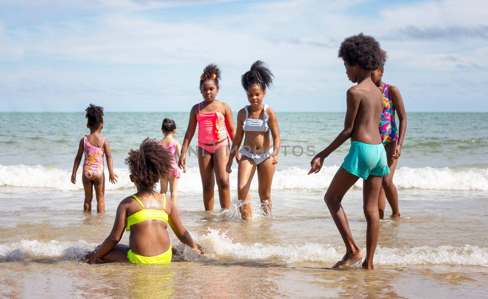 Kids playing running on sand at the beach, A group of children holding hands in a row on the beach in summer, rear view against sea and blue sky