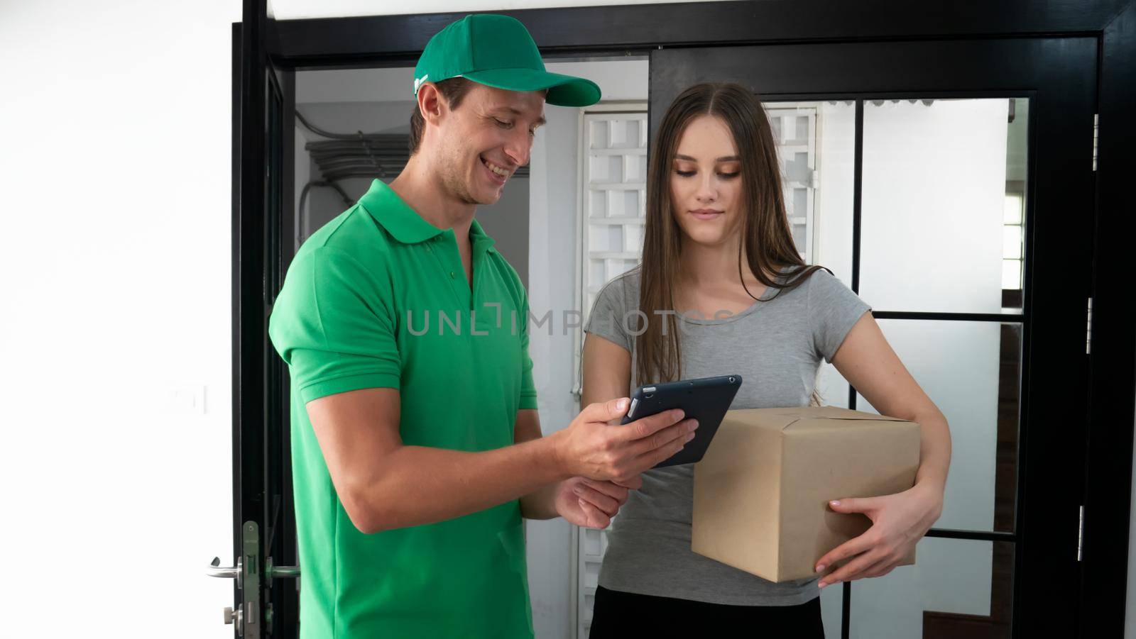 Young man delivering food to customer at doorway, Paper pocket and food containers in hands of a smiling deliveryman outdoors. Quality service of a restaurant.