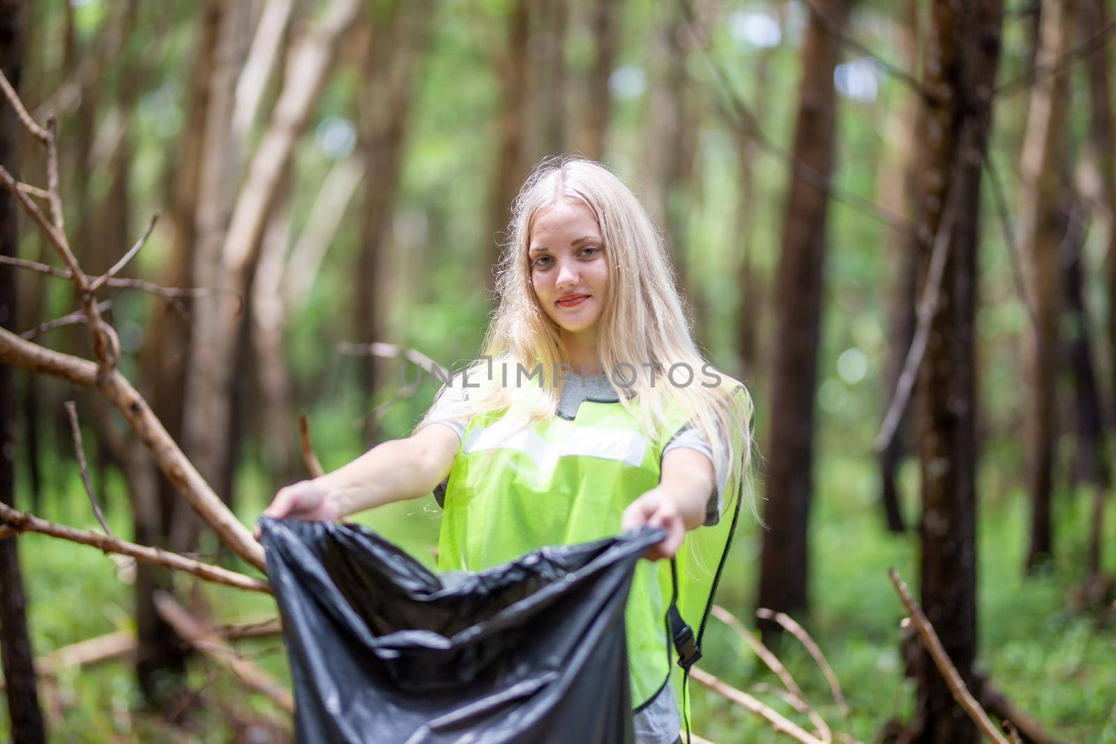 Green volunteering. Optimistic two volunteers holding garbage bag and help picking up trash at park, they're picking up the garbage and putting it in a black garbage bag. ecology protection concept.