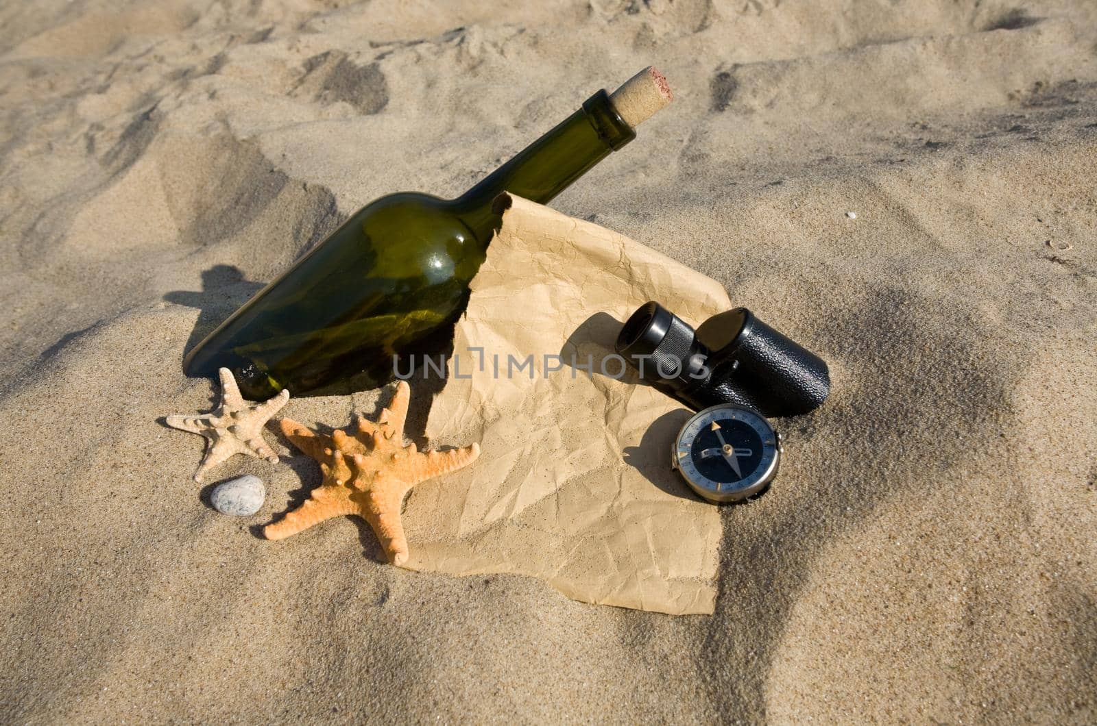 old paper, the compass, a sink and a bottle on sand background