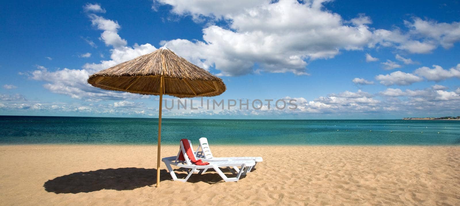 An attractive image of two chairs and umbrella on the beach