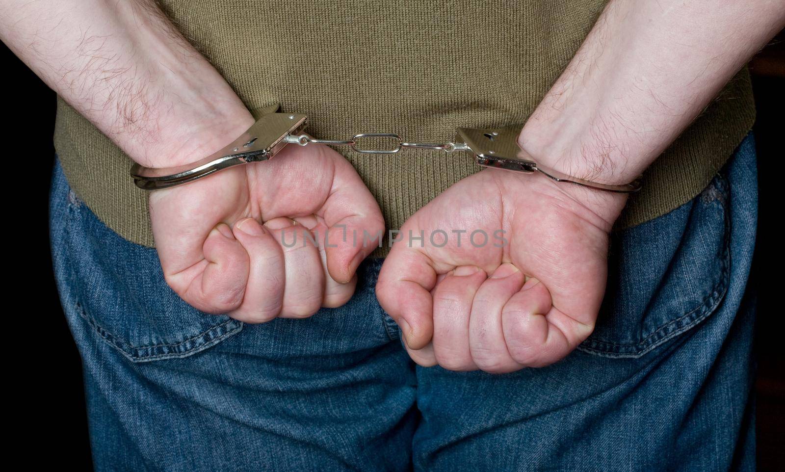 A mans hands in handcuffs behind his back