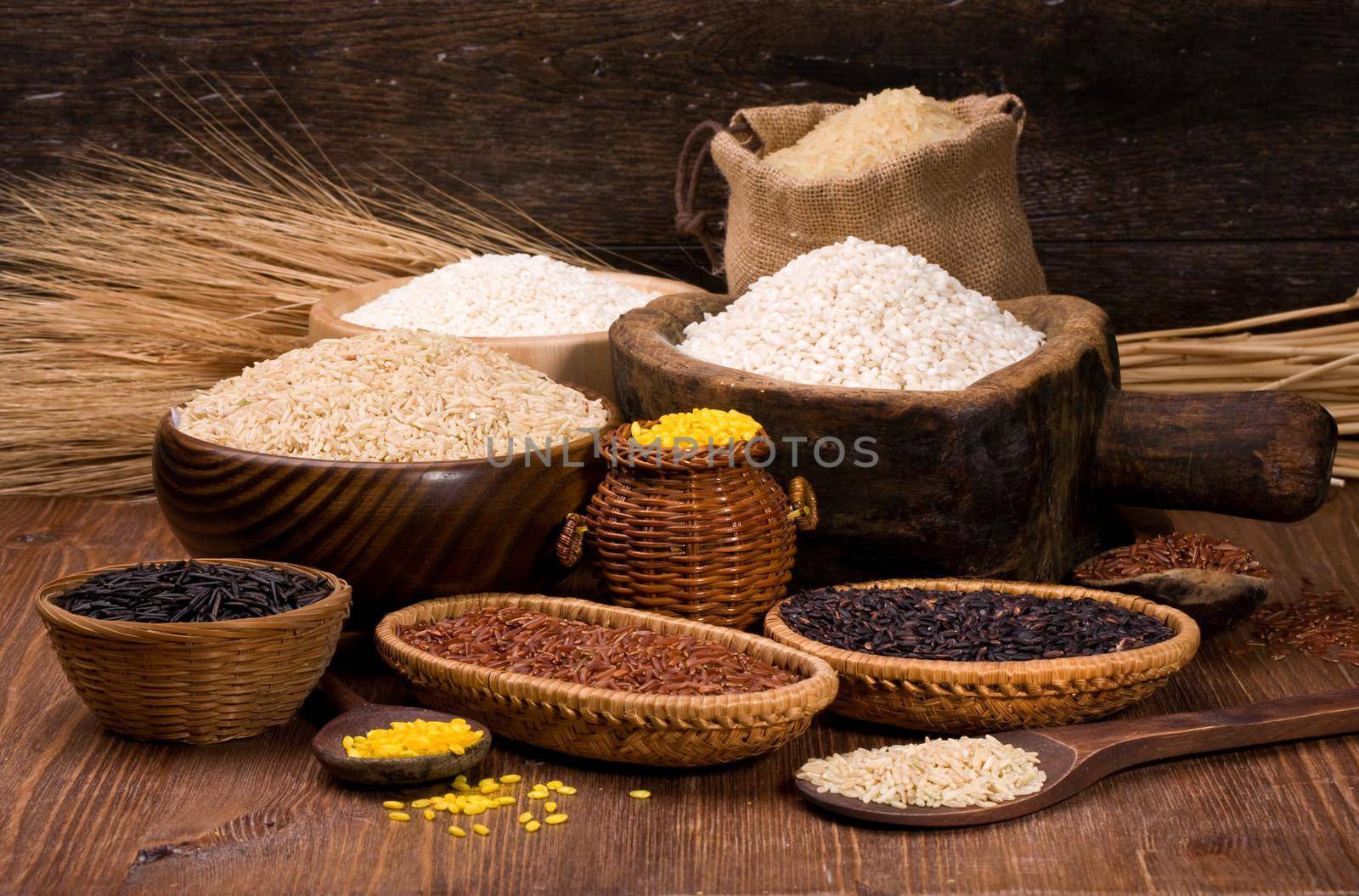 different varieties of rice in a wooden bowl on a background of dark wood