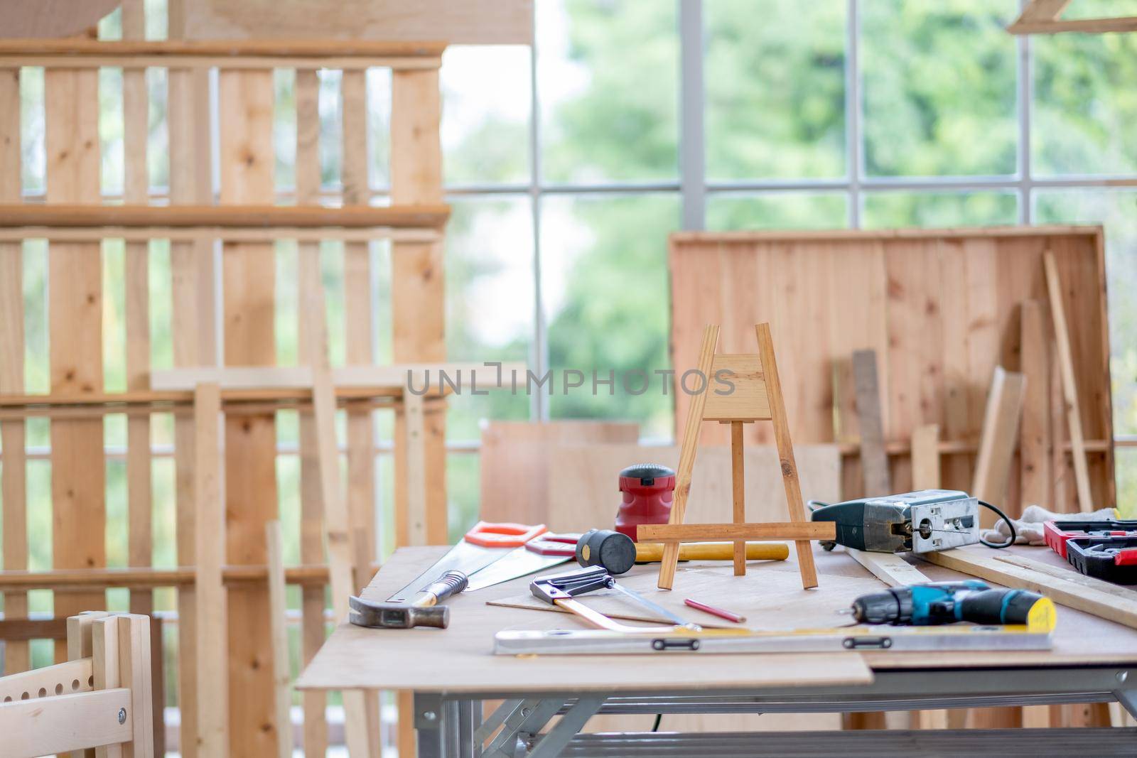 Room with woodwork are place inside and different types of tools and equipment are putting on table with day light and green garden as background.