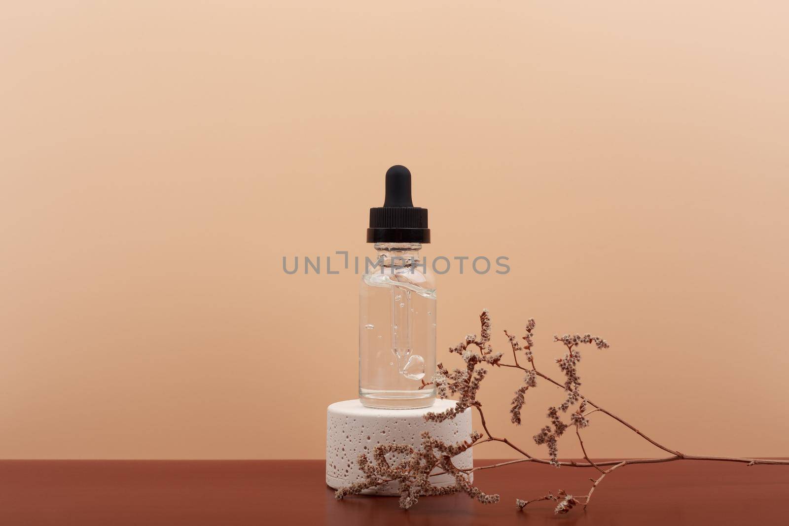 Skin serum for glowing, young looking skin and anti aging and moisturizing treatment on dark brown table against light beige background with copy space. 