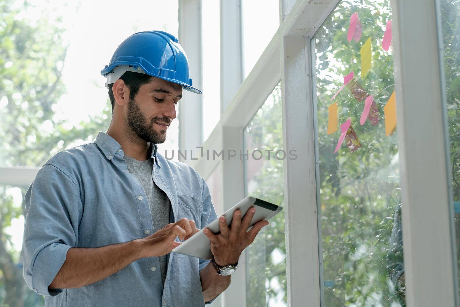 Caucasian engineer work in office with glass windows and use tablet to manage system also contact with other co-worker.