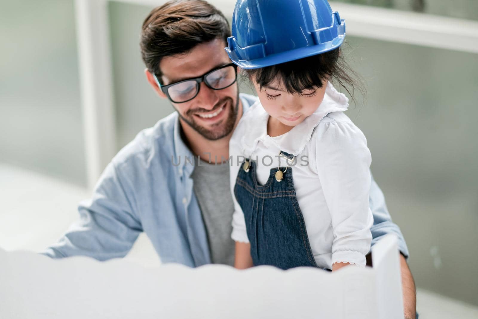 Main focus on little girl enjoy with her father during work at home and look to paper.