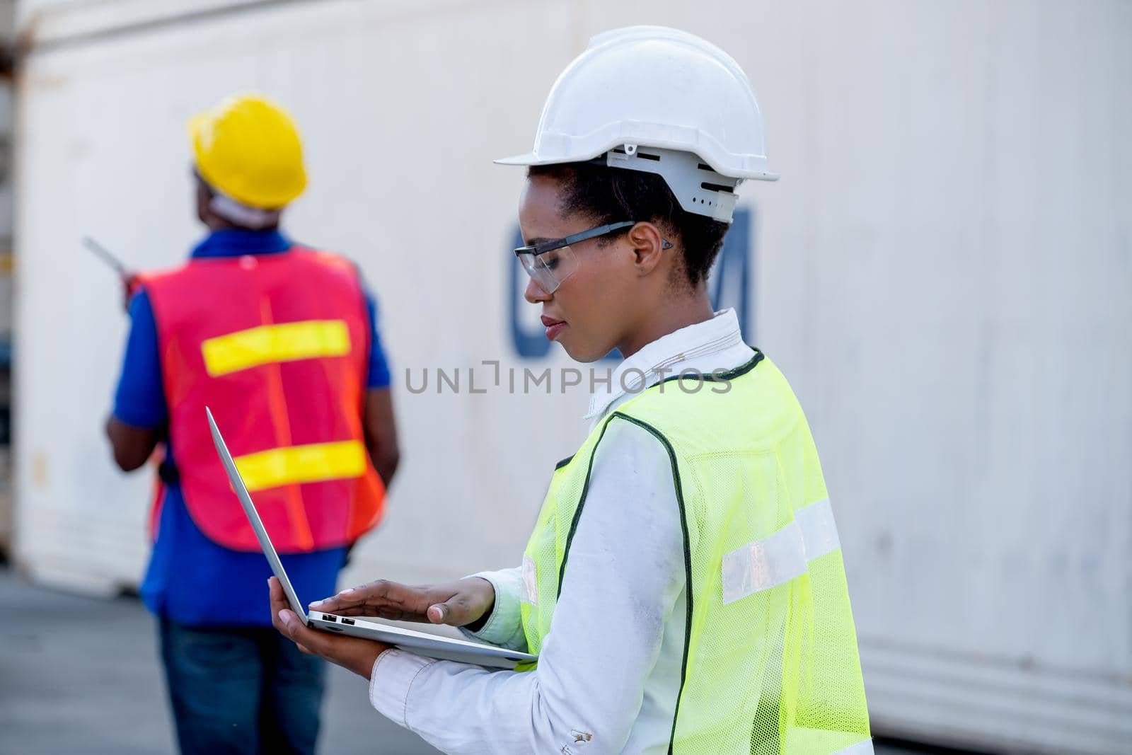 American African technician worker woman touch and look to laptop while her co-worker use walkie-talkie to communicate other. Concept of good system and manager support for better industrial business.