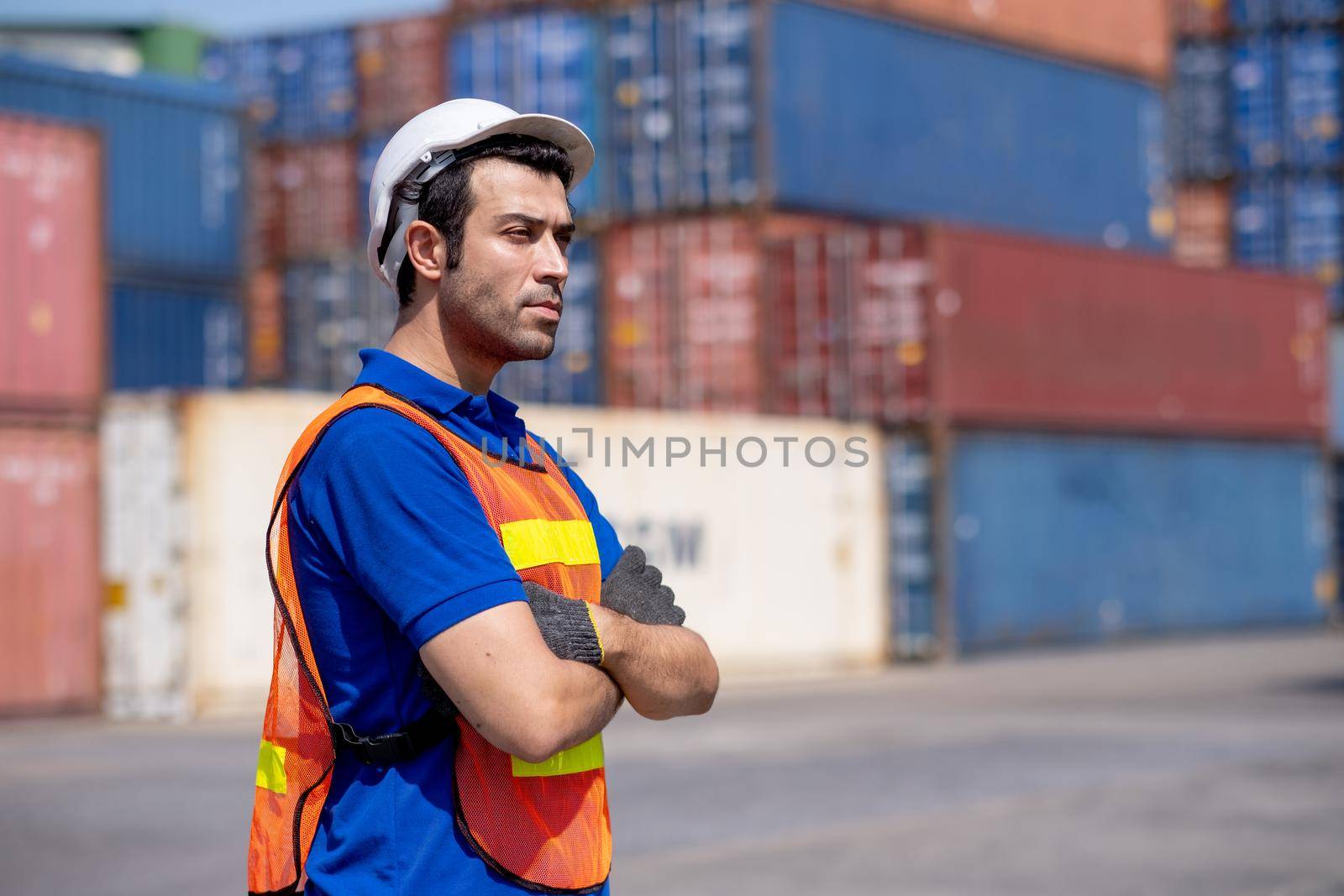 Portrait of engineer or foreman cargo container worker stand with arm-crossed in front of container tank stack with day light, factory and industrial worker support concept.